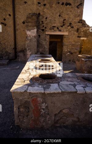 Thermopolis ou Taberna (magasin de cuisine) à Ercolano - Herculanum, ancienne ville romaine détruite par l'éruption du Vésuve ou Vésuve volcan. Banque D'Images