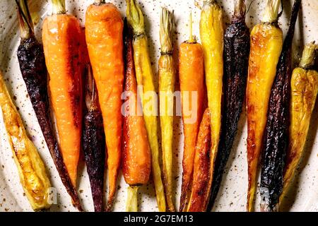 Des carottes de différentes couleurs grillées sur une plaque en céramique. Vue de dessus, plan d'appartement. Gros plan. Dîner végétalien Banque D'Images