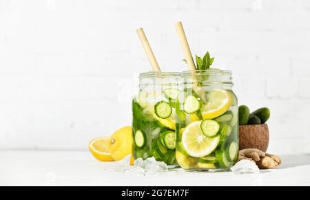 Détox d'été et boissons rafraîchissantes avec concombre, citron, menthe et gingembre sur fond de mur de briques blanches. Ombres ensoleillées Banque D'Images