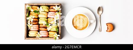 Macarons dans une boîte en bois avec fleurs printanières et une tasse de café plat Banque D'Images