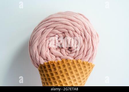 Gros plan de la pelote de fils de macrame rose dans un cône de crème glacée sur un fond blanc Banque D'Images