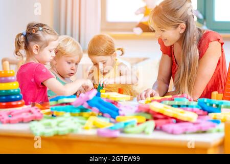 Groupe d'enfants jouant et enseignant à l'école maternelle jeux pratique Banque D'Images