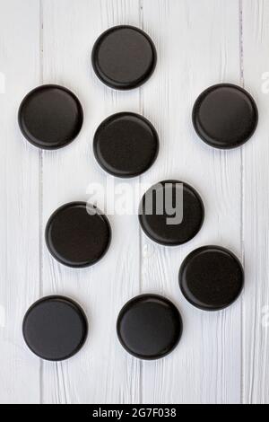 Pierres rondes noires polies sur un bureau en bois blanc. Banque D'Images