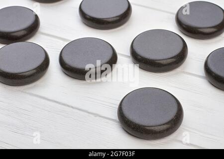 Gros plan en pierres rondes noires polies sur un bureau en bois blanc. Banque D'Images