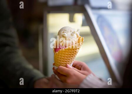 Cône de gaufrage de deux boules de crème glacée aux fruits à la main. Dessert d'été. Mise au point sélective. Scène réelle Banque D'Images