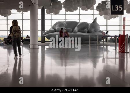 Les passagers marchent à côté d'une grande sculpture d'un chat inclinable dans le salon des départs de la Halle L du terminal 2e à l'aéroport Paris-Charles de Gaulle, France Banque D'Images