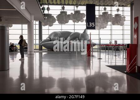 Un passager se tient près d'une grande sculpture d'un chat inclinable dans le salon de départ de Halle L du terminal 2e à l'aéroport Paris-Charles de Gaulle, France Banque D'Images