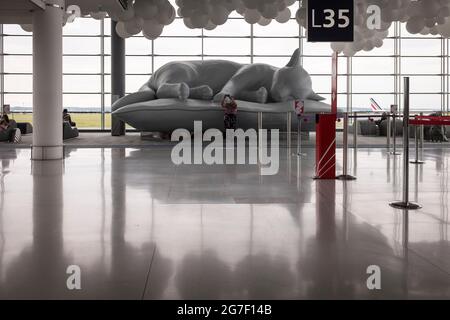 Une femme prend un selfie par une sculpture d'un chat endormi dans le salon de départ de Halle L du terminal 2e à l'aéroport Paris-Charles de Gaulle, France Banque D'Images