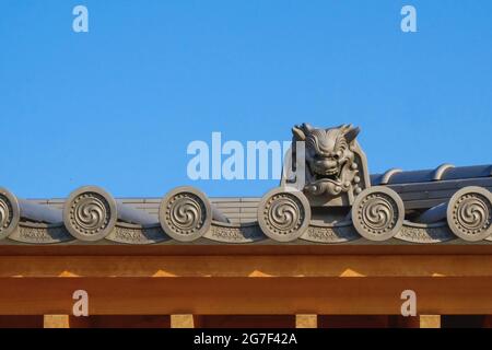 Fragment de toit japonais et coréen classique contre ciel bleu avec éléments décoratifs traditionnels et motifs répétables. Banque D'Images