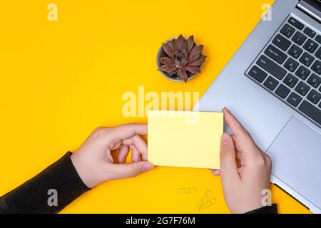 Femme main tenant des notes vierges écrire de nouvelles mises à jour de Messege idées à côté de l'ordinateur portable. Lady Palm montrant enveloppe pliage envoi de lettres adresse postale et Banque D'Images