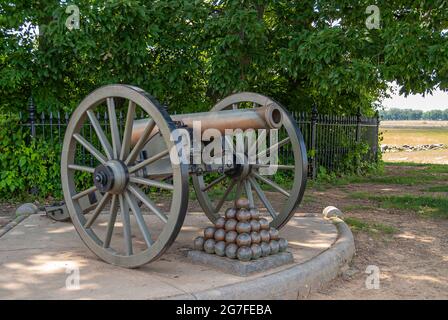 Gettysburg, PA, Etats-Unis - 14 juin 2008 : monuments du champ de bataille. Gros plan de canon brun-métallique avec pyramide de boules. Feuillage vert comme toile de fond. Banque D'Images