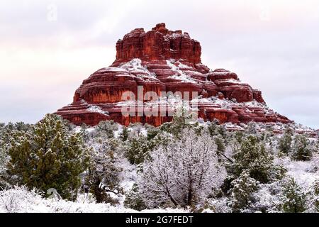 Bell Rock à Sedona, Arizona, entouré de neige fraîche en gros plan. Les falaises de grès de Sedona et le haut genévrier du désert et les pins dans le paysage d'hiver. Banque D'Images