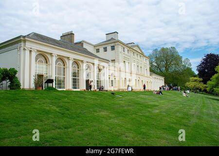 Les visiteurs s'assoient sur la rive menant à la façade sud de Kenwood House, une demeure ancestrale de Hampstead Heath, gérée par English Heritage. Banque D'Images