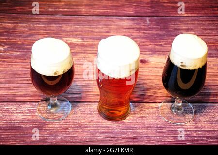 Trois verres avec différents types de bière foncée sont sur une table en bois. Gros plan. Banque D'Images