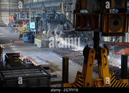 13 juillet 2021, Brandebourg, Eisenhüttenstadt: Laminoir à chaud d'ArcelorMittal. Les serpentins à bande chaude d'un poids maximal de 34 t sont produits à partir de dalles d'une épaisseur de 225 millimètres et d'une longueur maximale de 12 mètres. Photo: Soeren Stache/dpa-Zentralbild/dpa Banque D'Images