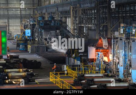 13 juillet 2021, Brandebourg, Eisenhüttenstadt: Laminoir à chaud d'ArcelorMittal. Les serpentins à bande chaude d'un poids maximal de 34 t sont produits à partir de dalles d'une épaisseur de 225 millimètres et d'une longueur maximale de 12 mètres. Photo: Soeren Stache/dpa-Zentralbild/dpa Banque D'Images