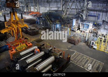 13 juillet 2021, Brandebourg, Eisenhüttenstadt: Laminoir à chaud d'ArcelorMittal. Les serpentins à bande chaude d'un poids maximal de 34 t sont produits à partir de dalles d'une épaisseur de 225 millimètres et d'une longueur maximale de 12 mètres. Photo: Soeren Stache/dpa-Zentralbild/dpa Banque D'Images