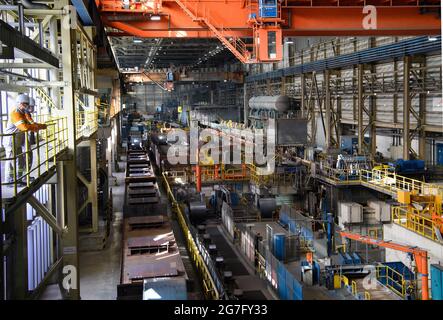 13 juillet 2021, Brandebourg, Eisenhüttenstadt: Laminoir à chaud d'ArcelorMittal. Les serpentins à bande chaude d'un poids maximal de 34 t sont produits à partir de dalles d'une épaisseur de 225 millimètres et d'une longueur maximale de 12 mètres. Photo: Soeren Stache/dpa-Zentralbild/dpa Banque D'Images