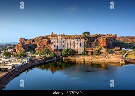 Le lac d'Agasthya et les collines rocheuses rouges environnantes. Quelques bâtiments de temple en pierre brune parsemés autour, Badami, Karnataka, Inde. Banque D'Images