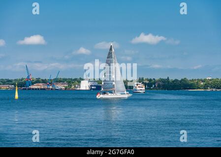 Kieler Förde, ein Segelboot BEI gutem Wind, im hintergrund die Werft von Friedrichsort, Eine Personenfähre der Kieler Fördeschifffahrt kreuzt das Fah Banque D'Images