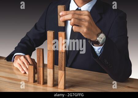 Homme d'affaires à la main en organisant le développement de blocs de bois d'empilement comme escalier d'étape, processus de réussite de croissance d'affaires, concept de croissance avec des blocs de bois, plan Banque D'Images