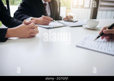 L'intervieweur ou le conseil lisant un curriculum vitae au cours d'une entrevue d'emploi, l'employeur interviewant un jeune homme candidat à un emploi pour le recrutement parlant au bureau moderne, Banque D'Images