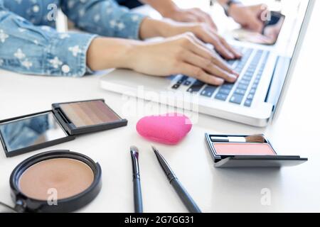 Maquillage et beauté blog, élégante femme mode blogger travaillant avec un ordinateur portable, beaucoup de cosmétiques et l'enseignement en ligne tutorial. Banque D'Images