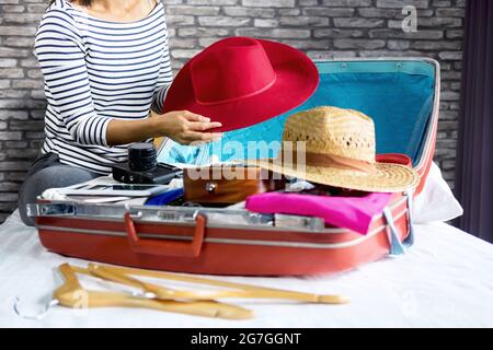 Voyage et de vacances concept, bonheur jeune femme emballage beaucoup de ses vêtements et de choses dans la valise sur le lit préparer pour le voyage et voyage à l'intérieur Banque D'Images