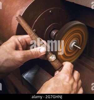 Un bijoutier polit une bague dorée sur une machine dans un atelier, en gros plan Banque D'Images