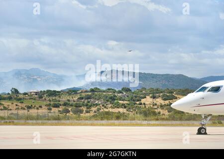 Vue sur un incendie dans les environs de l'aéroport d'Olbia Costa Smeralda avec des avions stationnés sur la piste Banque D'Images