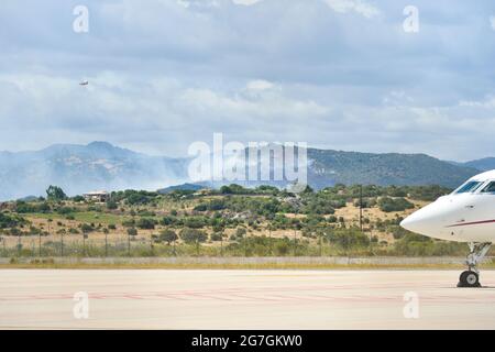 Vue sur un incendie dans les environs de l'aéroport d'Olbia Costa Smeralda avec des avions stationnés sur la piste Banque D'Images