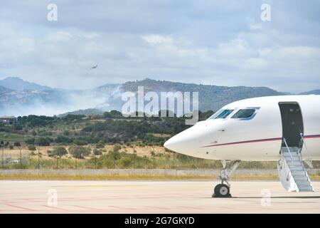 Vue sur un incendie dans les environs de l'aéroport d'Olbia Costa Smeralda avec des avions stationnés sur la piste Banque D'Images