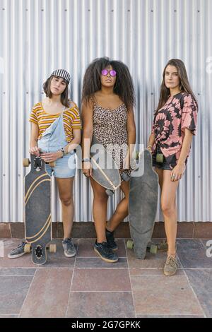 Trois belles jeunes femmes de différentes courses avec leurs longues planches à bord regardant la caméra Banque D'Images