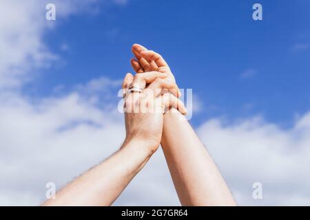 Faible angle des mains de la récolte personne méconnaissable avec un anneau sur le doigt contre le ciel bleu nuageux par beau temps d'été Banque D'Images