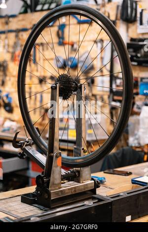 Roue de vélo sur support d'armature métallique placée sur l'établi dans l'atelier de réparation Banque D'Images