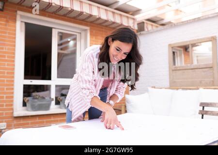 Femme architecte positive debout à la table tout en analysant et pointant vers le plan pendant le travail sur le projet Banque D'Images