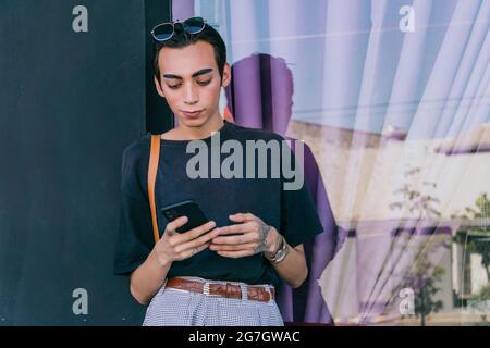 Déterminé femme aux cheveux teints portant des vêtements tendance debout rue et regarder la caméra Banque D'Images