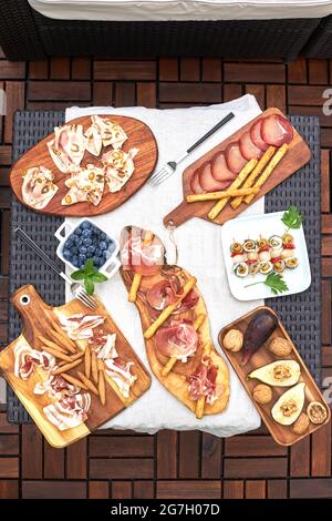Table aménagée sur une terrasse avec divers hors-d'œuvre délicieux tels que jambon serrano, broché, noix, etc Banque D'Images