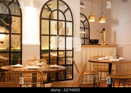 Tables en bois et chaises en osier placées dans un restaurant spacieux et confortable à l'intérieur moderne Banque D'Images