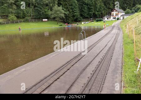 14 juillet 2021, Saxe, Jöhstadt: Des travaux de nettoyage sont en cours après une inondation éclair dans le district de Jöhstadt, à Steinbach, dans l'Erzgebirgskreis. Le lendemain de l'inondation éclair, les résidents, les chantiers de construction, les pompiers et les agents de secours sont occupés à nettoyer. Les débris entrants bloquent toujours les évacuations. L'un des habitants de Jöhstädt a été balayé par l'inondation éclair, il est toujours absent. Photo: Ronny Küttner/dpa Banque D'Images