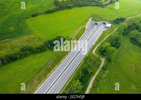 Vue de dessus sur l'entrée du tunnel de l'autoroute recouverte d'herbe verte Banque D'Images