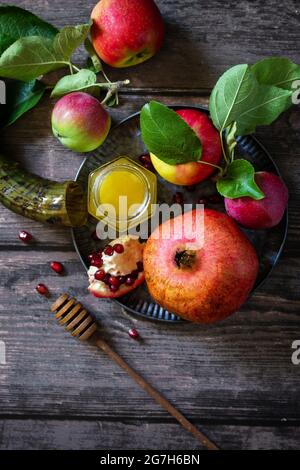 Image religieuse du concept de Rosh hashanah (vacances du nouvel an juif). Symboles traditionnels : miel, pommes et grenade sur une table rustique sombre. Vue de dessus Banque D'Images