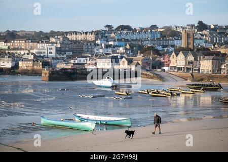 St Ives, Cornwall, Royaume-Uni. 24 avril 2021. Tôt le matin, les propriétaires de chiens marchent le long de la plage de St Ives à Cornwall sur ce qui promet d'être une journée chaude. Banque D'Images