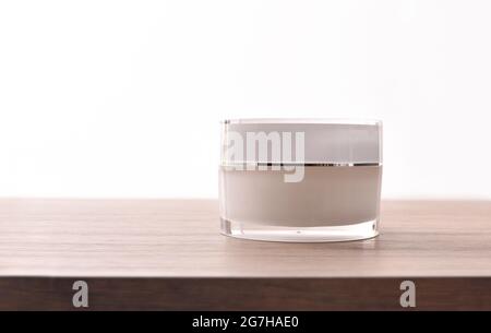 Pot à cosmétiques en verre fermé avec couvercle en plastique sur table en bois. Vue avant. Banque D'Images