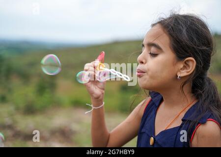 Jeune fille gamin jouant en soufflant des bulles d'eau de savon - conepte de chidlren ludique pendant les vacances. Banque D'Images