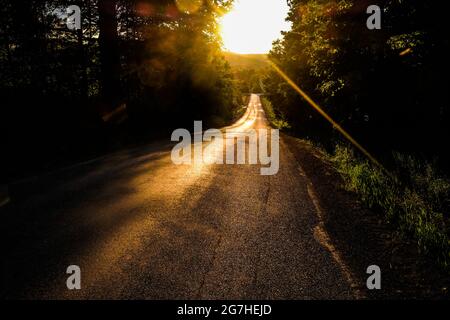 Coucher de soleil sur une route d'asphalte rurale près de Cooperstown, New York, États-Unis. Banque D'Images