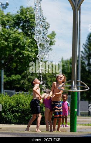 Trois enfants jouent dans des jeux aquatiques et des fontaines à Québec, au Canada Banque D'Images