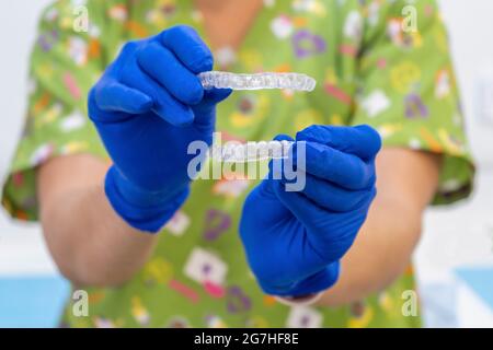 Médecin tenant deux aligneurs dentaires transparents et une garde de nuit dentaire. Banque D'Images