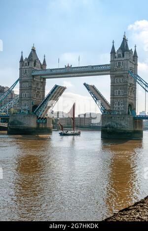 Barge à voile de la Tamise Ardwina passant sous Tower Bridge enjambant la Tamise avec la chaussée relevée pour faciliter sa voile en début de matinée estivale Banque D'Images