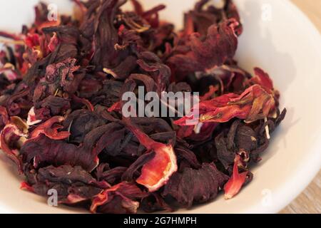 Le thé Roselle s'est offert sur une assiette blanche. Bol blanc avec fleur de thé hibiscus. Fleur d'hibiscus séchée Banque D'Images